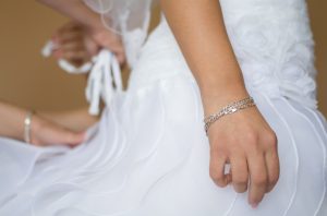 Bride Waiting Patiently while Her Assistant Adjusts Wedding Dress